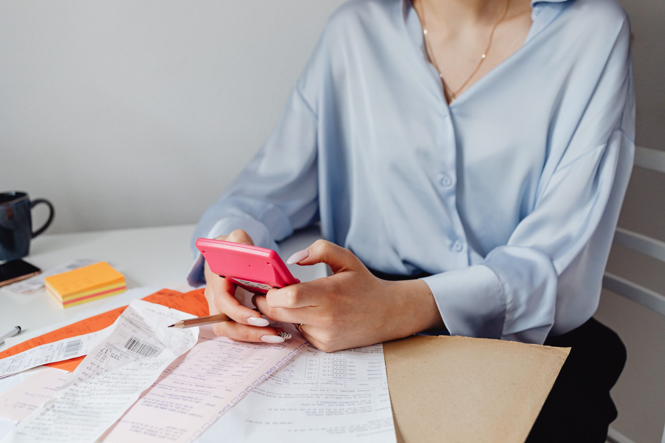 Femme utilisant calculatrice rose entouree de factures